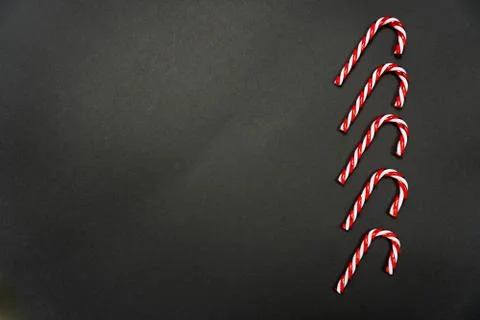 Five candy canes laying in a row on black background Stock Photos