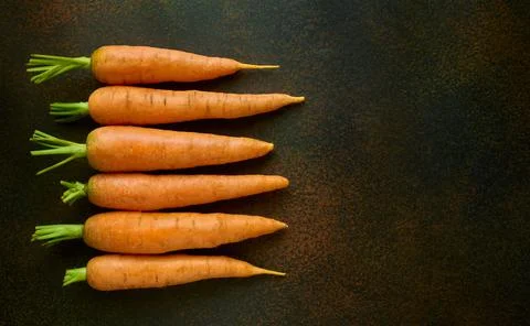Five carrots on a dark background, top view, flat lay Stock Photos