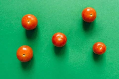Five cherry tomatoes on a green background. Stock Photos