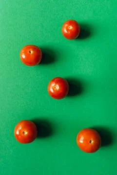 Five cherry tomatoes on a green background. Stock Photos