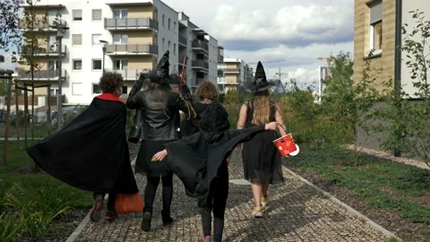 Five children of different ages in black masquerade costumes go from house to Stock Footage 141190527