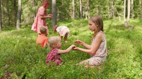 Five children picking wild berries together in a green forest in slow motion Stock Footage 317751984