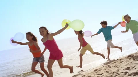 Five children running by camera on beach holding balloons. Stock Footage 43672807