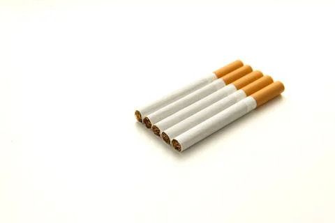 Five cigarettes with yellow filter are lying on a flat white surface Stock Photos