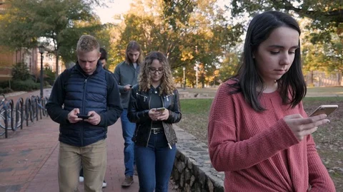 Five college students walking and looking down at their mobile phones on campus Stock Footage 104364521