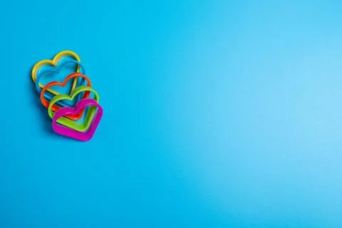 Five colored cookie cutters for making cookies in the form of hearts on a blu Stock Photos
