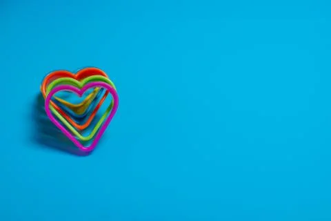 Five colored cookie cutters for making cookies in the form of hearts on a blu Stock Photos
