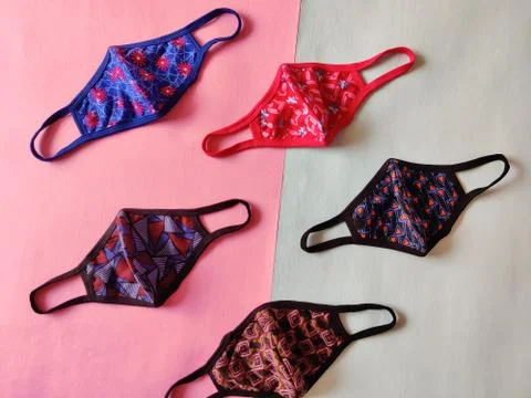 Five different colored printed face masks isolated on green and pink backgrou Stock Photos