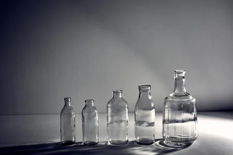 A five different empty glasses bottles with copy space. Graphic still life with Stock Photos