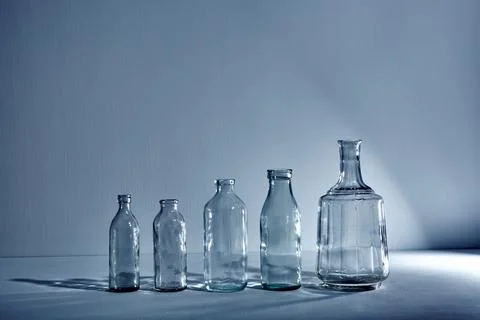 A five different empty glasses bottles with copy space. Graphic still life wi Stock Photos