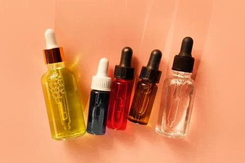 Five different glass dropper bottles with serum, oil, gel and beauty products on Stock Photos