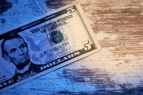 Five-dollar bill in the shadow, and part in the light, tax evasion, taxes in  Stock Photos