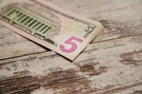 A five-dollar bill on a worn table close-up Stock Photos