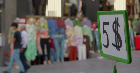 Five dollar price tag in foreground for discounted clothing sold on street in Stock Footage 231258855
