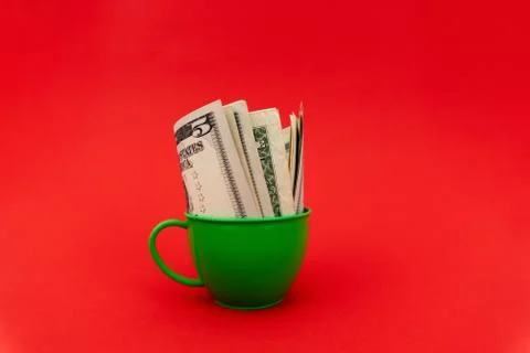 Five dollars in green cup at red background. Stock Photos