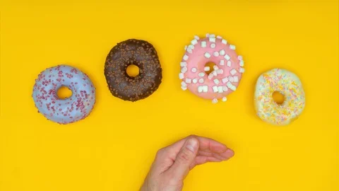 Five donuts dancing, male hand moving them away. Healthy concept. Stop motion Stock Footage 128922827