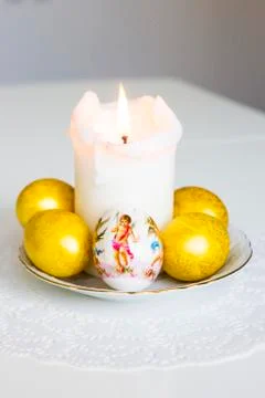 Five easter eggs and white candle on the table Stock Photos
