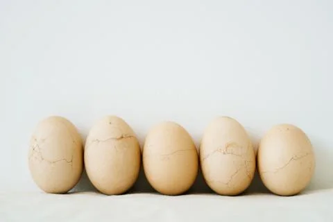 Five Easter eggs trendy pastel colored with cracked shells on a white table a Stock Photos