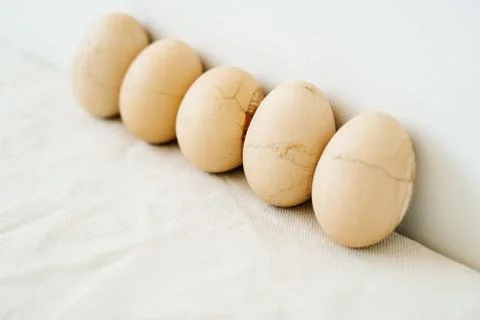 Five Easter eggs trendy pastel colored with cracked shells on a white table a Stock Photos
