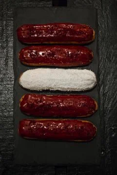 Five Eclairs on Dark Slate Board with Red and White Toppings Stock Photos