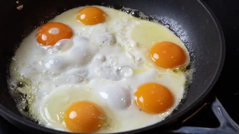 Five eggs sizzling in a pan with handle in view Stock Footage 301543159
