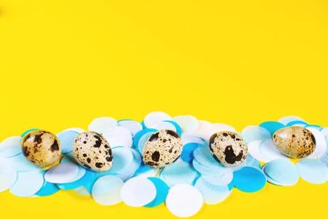 Five eggs on yellow background with confetti. Stock Photos
