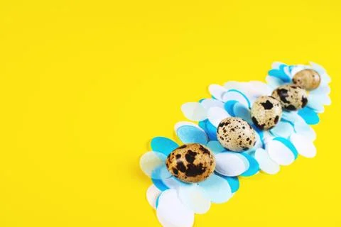 Five eggs on yellow background with confetti. Stock Photos