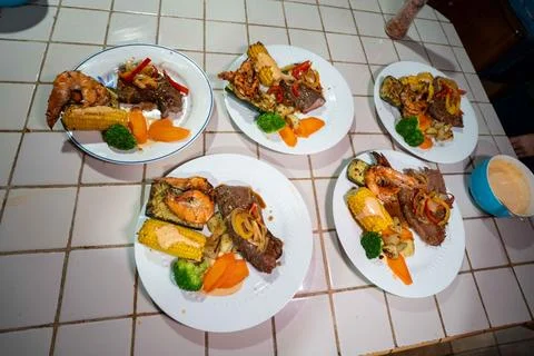 Five entrees of shrimp, steak, corn, and veggies at a rustic central americ.. Stock Photos