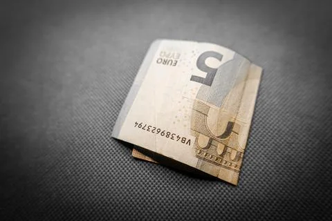 Five euro note gently placed on a vibrant green surface Fotos de archivo