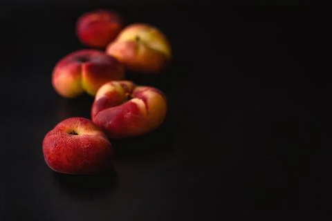 Five fig nectarines lie in a zigzag pattern on a black background Stock Photos