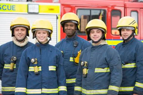 Five firefighters standing by fire engine wearing helmets Stock-Fotos