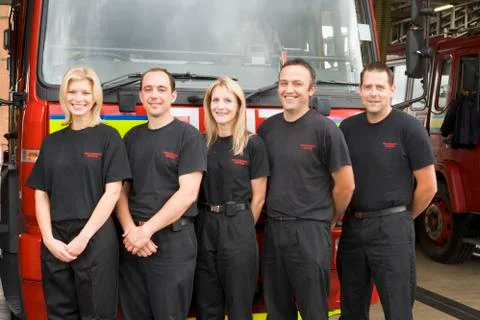 Five firefighters standing in front of fire engine Stock Photos