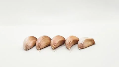  Five fresh garlic cloves arranged in a horizontal row isolated on white s.. Stock Photos