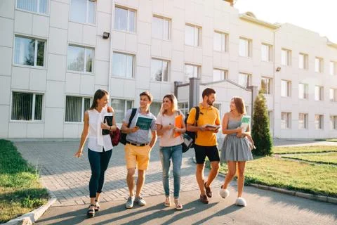 Five friendly students are walking after they passed test outside the college Stock Photos