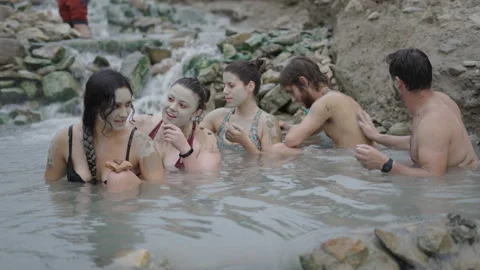 Five friends in a row put mud on each others backs in the water. Stock-Footage 221546640