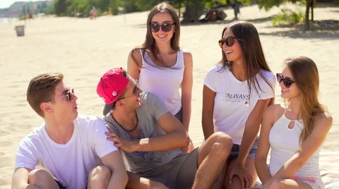 Five friends sitting at mat at beach talking and laughing Stock-Footage 67349024