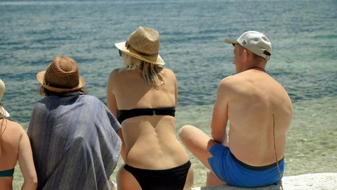 Five friends sitting on a sandy beach near the Mediterranean sea. Greece. 4K Stock Footage 118073204