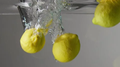 Five full lemons dropped in clear water slow motion Stock Footage 132891176
