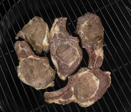 Five half-roasted pork chops on a gas grill Stock Photos
