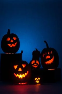 Five Halloween pumpkins, merry faces on a blue background. Stock Photos