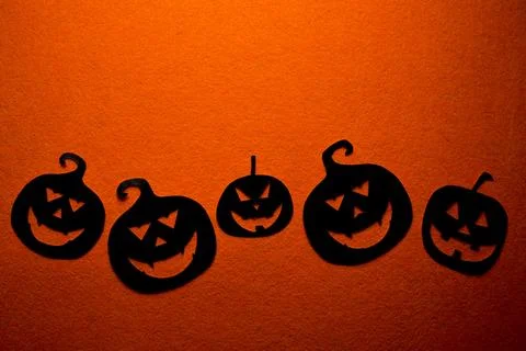 Five hand-painted black pumpkins on an orange background Stock Photos