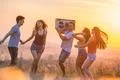 The five happy people dancing on the hill on the sunset background Photo