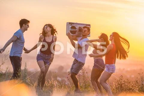 The five happy people dancing on the hill on the sunset background Stock Photos