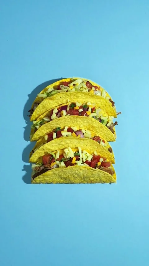 Five hard shell beef tacos on light blue background Stock Footage 331780935
