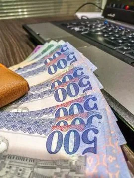 Five hundreds notes in a raw in treasury office and laptop in background Stock Photos