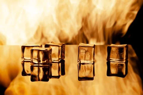 Five ice cubes on a black background, in the background flames Stock Photos
