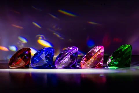 Five illuminated diamond-shaped crystals, each with a distinct color Foto stock