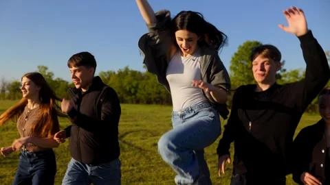 Five joyful friends skipping and running through a rural meadow field Stock Footage 334560238