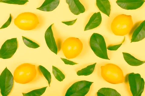Five lemons with lemon tree leaves on yellow Stock Photos