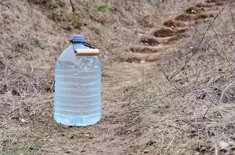 Five-liter containers with clear clean drinking water on the side of the road Stock Photos